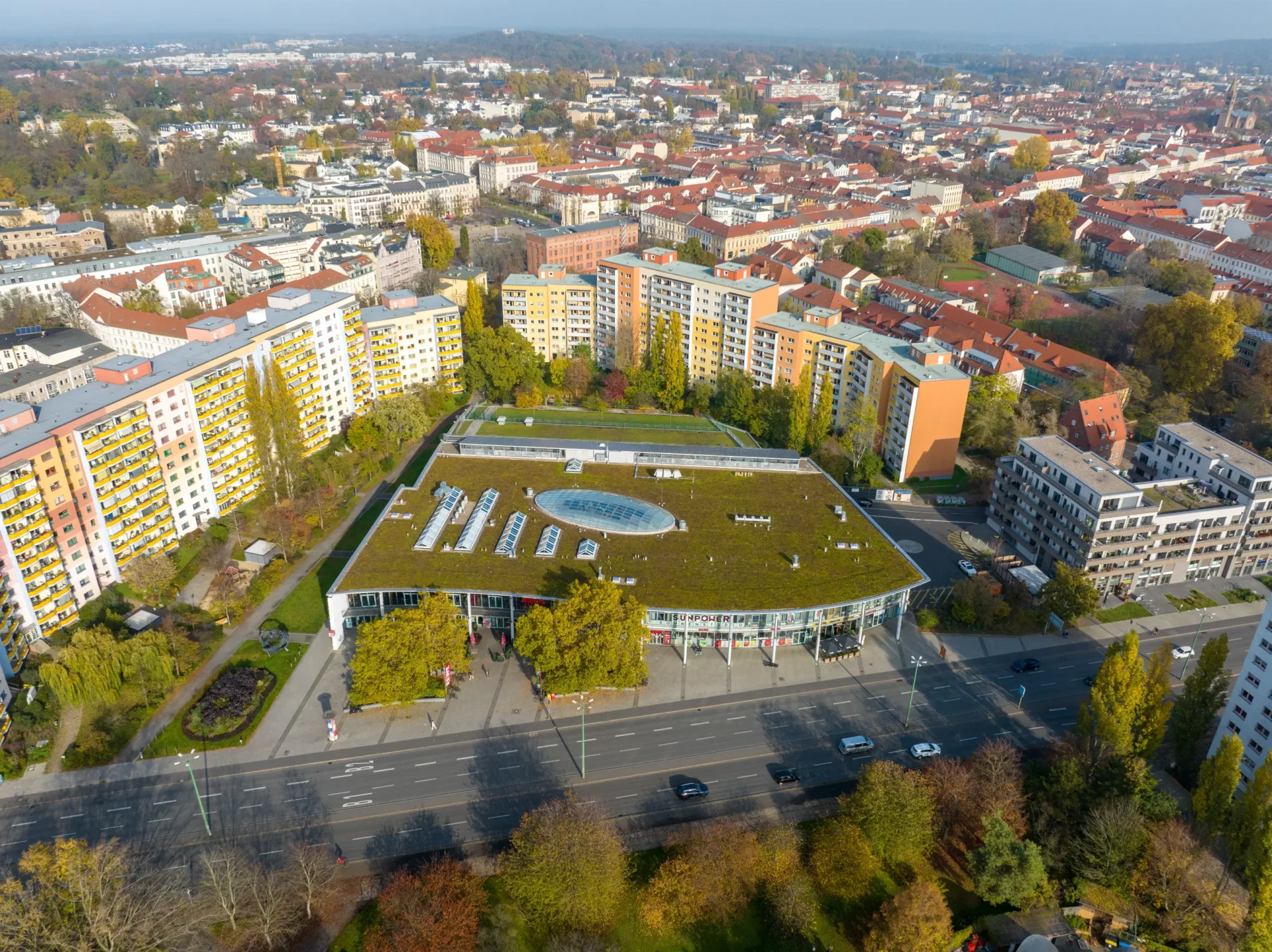 A Building With A Green Roof Surrounded By Buildings